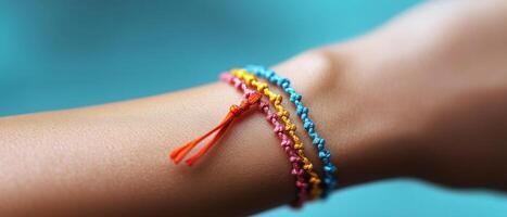 Colorful Handmade Friendship Bracelets on Wrist Against Blue Background, Close-Up of Vibrant Woven Accessories photo