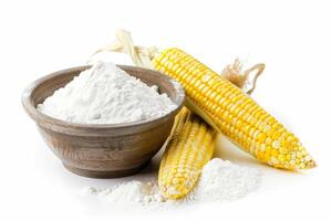 Corn cobs lying near wooden bowl filled with flour on white background photo