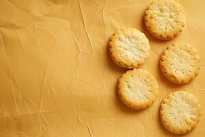 Five round cracker cookies are lying on a crumpled yellow background with copy space photo