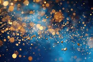 Golden particles exploding creating a festive bokeh effect on blue photo
