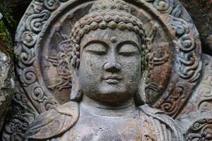 Ancient stone buddha statue meditating with eyes closed photo