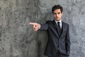 Serious businessman pointing with finger against grey background photo