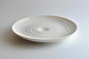 White empty plate with concentric circles is standing on white table photo