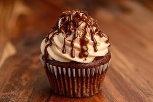 Delicious chocolate cupcake with chocolate drizzle sitting on wooden table photo