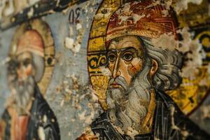 Ancient byzantine fresco depicting a saint wearing a red hat in a monastery photo