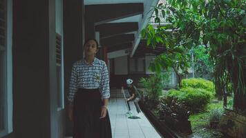 Person standing in corridor with greenery and background activity video