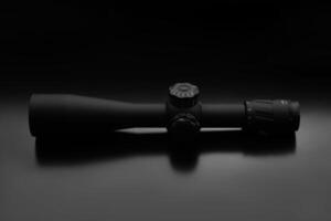 Modern sniper scope on a dark back. Optical device for aiming and shooting at long distances. photo