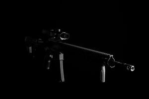 Modern automatic carbine with collimator sight isolate on dark back. Weapons for the army, police and special forces. photo