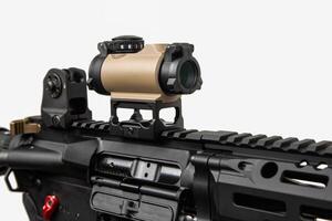Close-up of a red dot sight on an automatic rifle. Weapons for police, special forces and the army. A carbine with red dot sight and silencer on a white back photo