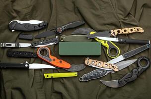 A variety of folding and pocket knives lie on khaki fabric. A versatile pocket tool and self-defense tool. photo