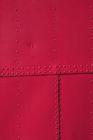 A metal surface made of several sheets connected with rivets. Viva magenta color back. photo