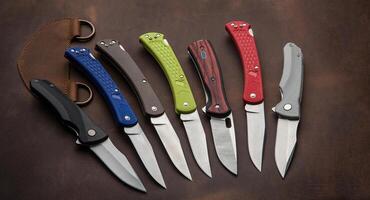 Multi-colored penknives on a brown leather background. Different folding knives lie on a large piece of brown leather. photo