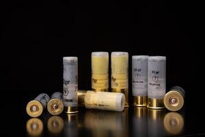 Shotgun cartridges on a dark surface with reflections. Ammunition for smooth-bore weapons on a black back photo