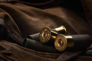 Shotgun shells close-up. Ammunition for smoothbore weapons on a khaki canvas backpack. Dark back photo