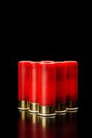 Shotgun shells on a black reflective surface. Ammunition for 12 gauge smoothbore weapons. Hunting ammunition. Dark back. photo