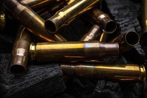 Empty shells from weapons on black smoldering coals. Consequences of the war. Dark back. photo