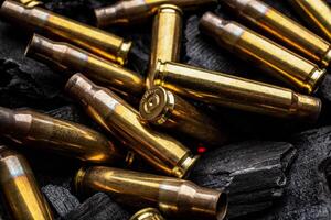 Empty shells from weapons on black smoldering coals. Consequences of the war. Dark back. photo