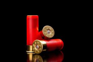 Shotgun shells on a black reflective surface. Ammunition for 12 gauge smoothbore weapons. Hunting ammunition. Dark back. photo