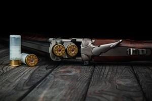 Classic trigger double-barreled hunting rifle on a wooden background. Concept postcards for hunters. Smooth-bore hunting rifle open for reloading. photo