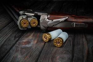 Classic trigger double-barreled hunting rifle on a wooden background. Concept postcards for hunters. Smooth-bore hunting rifle open for reloading. photo