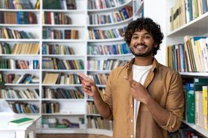 A man, elegantly dressed, is confidently pointing at something unseen in a library. His posture suggests a presentation or a guide in an educational setting surrounded by an array of books. photo