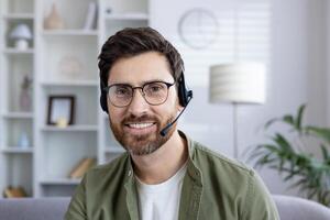 Smiling man with headset engaged in a virtual meeting from his modern home office. Business and technology concept. photo