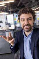 Businessman in modern office engaged in call looking at camera smiling, discussing or presenting. Professional setting with contemporary work environment. photo