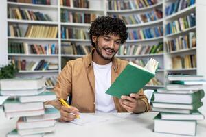A cheerful graduate student with curly hair is immersed in exam preparation, surrounded by stacks of books at a campus library. He takes notes and reads intently, conveying a sense of learning and academic dedication. photo