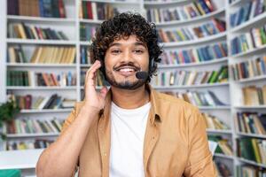 A cheerful young man wearing a headset and smiling as he looks at the camera, likely engaging in a call or as a student in a virtual class. photo