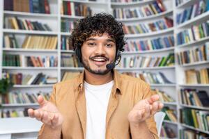 A young man in casual attire stands with an open gesture in a library setting, symbolizing concepts of choice, decision-making, education, and the vast world of knowledge. photo