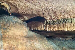 A rock wall with a brown and tan color. The wall is made of rocks and has a rough texture. photo