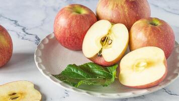 a plate with apples and a leaf on it photo