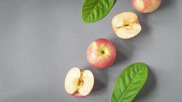 a group of apples with leaves on a gray surface photo