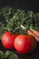 two tomatoes and a carrot on a table photo