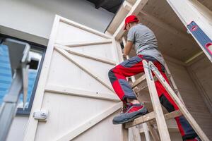Man Repairing Wooden Door While Standing on a Ladder in a Residential Setting photo