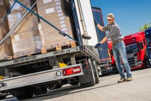 Trucker Loading Cargo Boxes Into Truck photo
