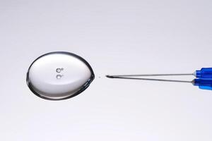 A drop of medicine flowing from a syringe with a needle. photo