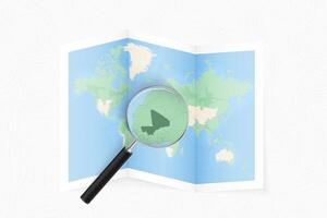 Enlarge Mali with a magnifying glass on a folded map of the world. vector