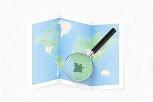 Enlarge Angola with a magnifying glass on a folded map of the world. vector