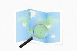 Enlarge Rwanda with a magnifying glass on a folded map of the world. vector