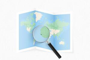 Enlarge Guinea-Bissau with a magnifying glass on a folded map of the world. vector