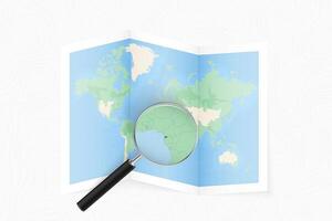 Enlarge Equatorial Guinea with a magnifying glass on a folded map of the world. vector