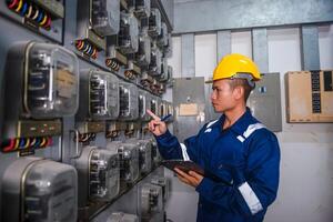 eléctrico mantenimiento ingeniero es comprobación electricidad metro, principal distribución tablero y escribir abajo valor de electricidad en un portapapeles foto