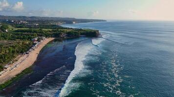 Scenic coastline with ocean and perfect swell waves. Drone view of Bali landscape video