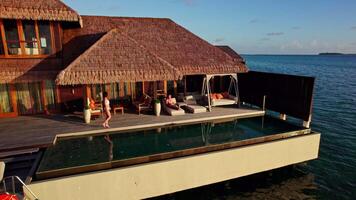 Couple relaxing in a bungalow on the water in the Maldives video