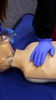 Training reanimation procedure on a mannequin. People use breathing apparatus on a dummy's face during practice course. Training for giving first aid to a patient. Vertical video
