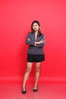 Cool asian female executive in gray suit with long hair, white skin, taking photo in studio with red background standing with her arms crossed. for corporate concepts, fashion and advertising