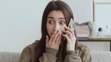 Unbelievable news. Surprised girl getting pleasant information by phone, sitting on quarantine at home video