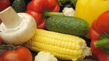 A variety of fresh vegetables, including bell peppers, cucumbers, corn on the cob, mushrooms, and tomatoes. The vegetables are arranged in a colorful and appealing way in a market stall. video
