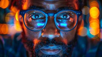 A man with glasses is staring at the camera. The image has a moody and mysterious feel to it, as the man's gaze seems to be focused on something beyond the frame photo